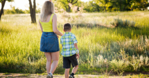 A mother walking next to her son looking out on a grassy field.