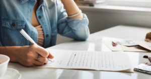 Teen girl sitting at a table writing about her emotions