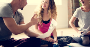 Father, teen daughter and mother all sitting on the floor together reviewing homework